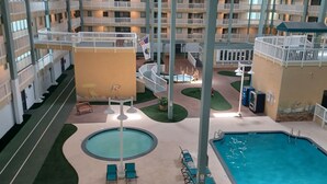 A hotel atrium with multiple balconies, a central pool area with lounge chairs, and a children's play area. -  Updated Oceanfront 2 br. getaway balcony view, steps to pool, walk to beach! (Hilton Head Island)