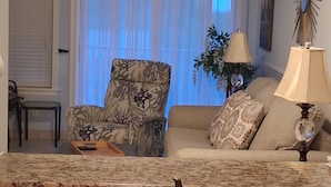 A living room with a sofa, armchair, and a dining area with a granite countertop and sink. -  Updated Oceanfront 2 br. getaway balcony view, steps to pool, walk to beach! (Hilton Head Island)