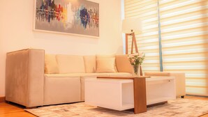 Ein modernes Wohnzimmer mit einem beigen Sofa, einem weißen Couchtisch und einem Gemälde einer Stadtansicht.