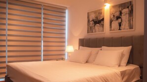Ein ordentlich bezogenes Bett mit weißen Leinentüchern, einem grauen Kopfteil und zwei abstrakten Bildern an der Wand.