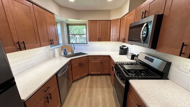 Una cocina moderna con armarios de madera, estufa de acero inoxidable y un amplio ventanal.