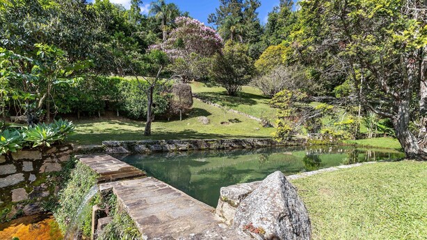Ein friedlicher Garten mit Teich, Steinbrücke und üppigem Grün.
