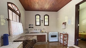 Una cocina con techo de madera, suelo de baldosas y estufa.