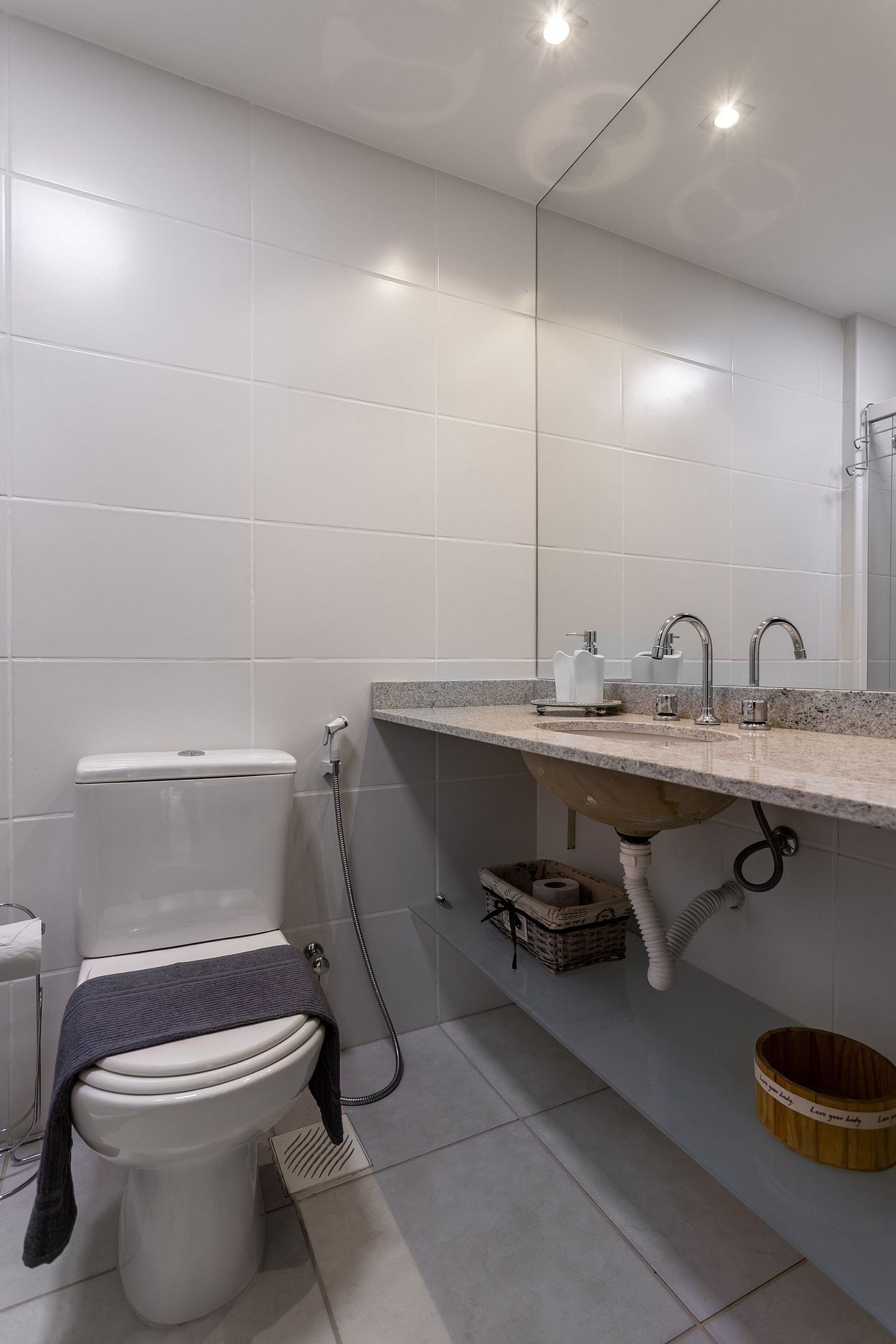 Een moderne badkamer met toilet, wastafel en spiegel.