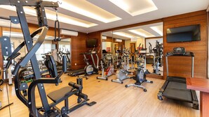 A gym with various exercise equipment, a treadmill, and a mirrored wall.