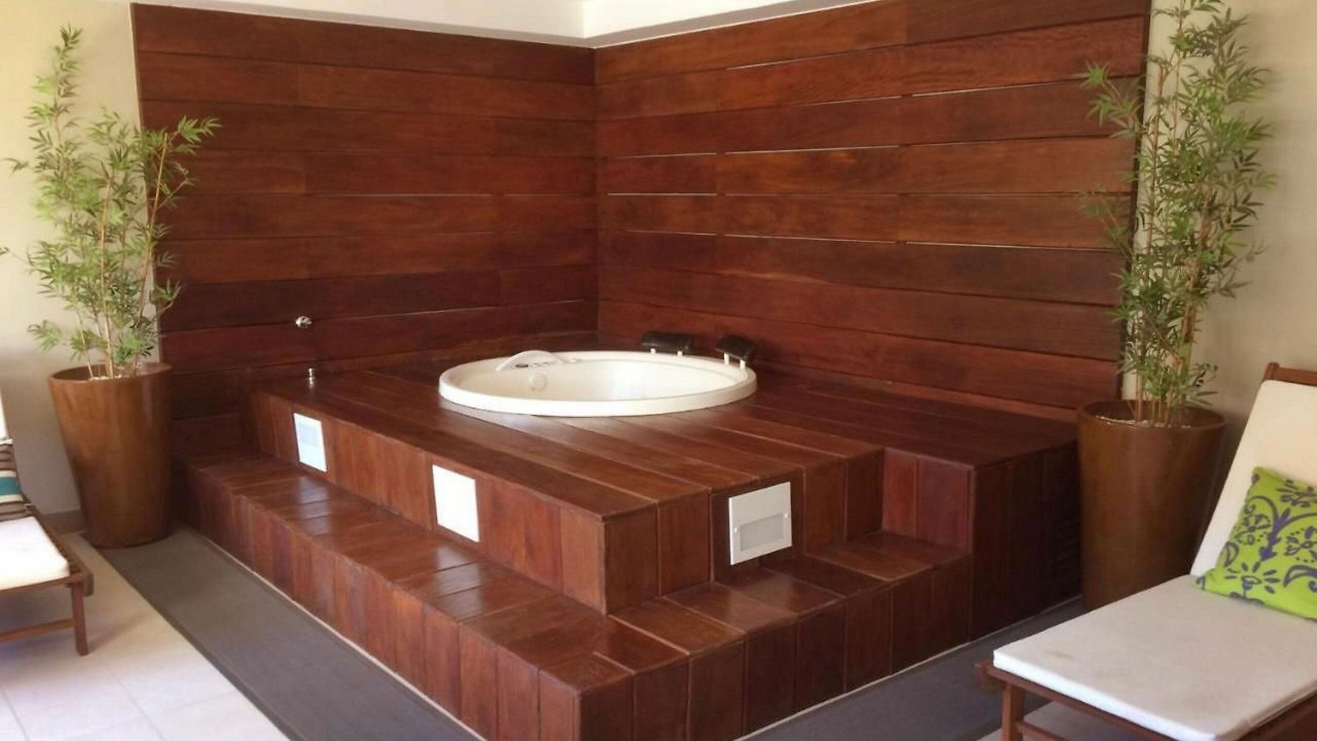Ein Badezimmer mit einem Holzbadezimmermöbel, einer Badewanne und zwei Blumentöpfen.