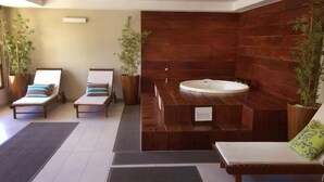 A spa area with two sun loungers, a hot tub, and potted plants.