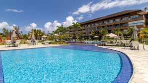Un hotel con una piscina grande, asientos al aire libre y palmeras.