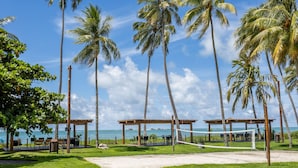 A beach volleyball court with palm trees and a view of the ocean.