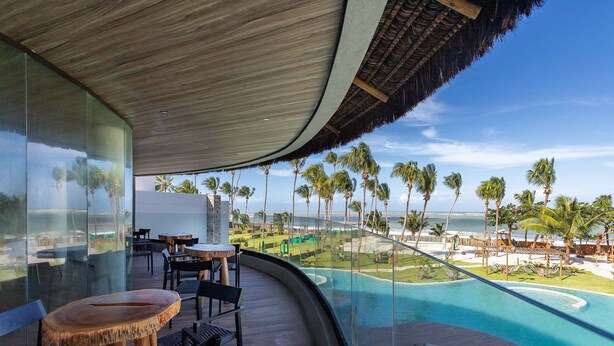 Un complexe hôtelier moderne doté d’un balcon incurvé offrant une vue sur une piscine et une plage.