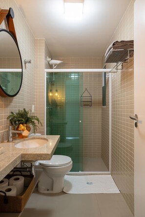 Ein modernes Badezimmer mit Duschkabine aus Glas, Waschbecken mit Spiegel und Toilette.