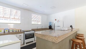 Et moderne køkken med hvide skabe, en granitbordplade, en indbygget komfur og en kaffestation.