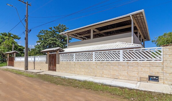 A two-story building with a tiled roof and a white fence.