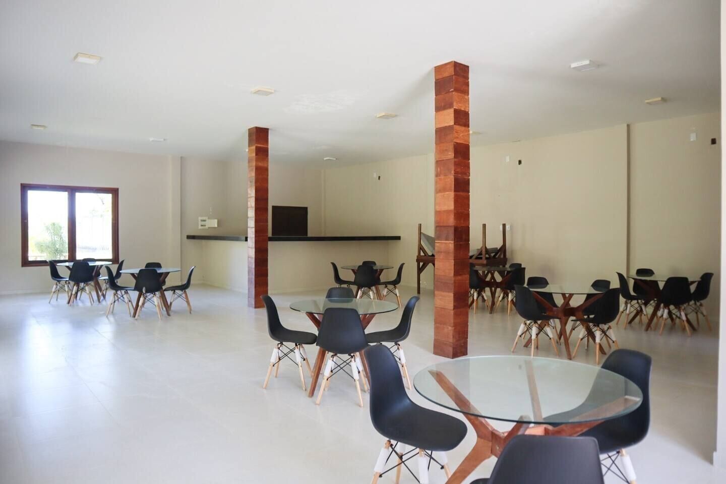 Una amplia sala de conferencias con múltiples mesas y sillas, ventanas grandes y un techo alto.