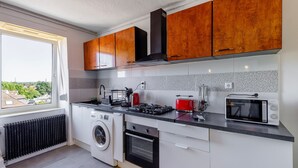 A modern kitchen with a washing machine, oven, microwave, and a view of the outside.