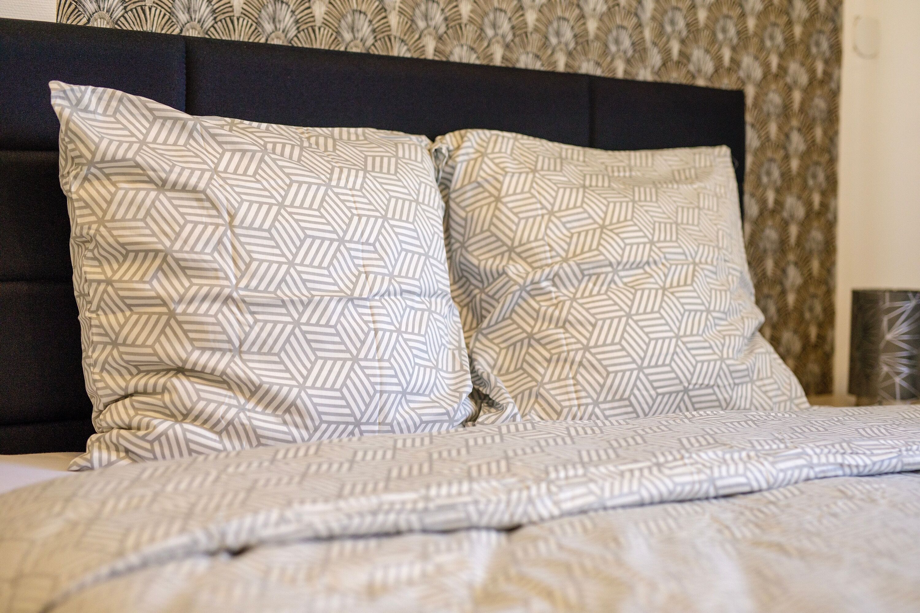 A bed with patterned pillows and a matching blanket.