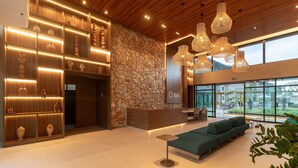 A modern lobby with a stone wall, wooden shelves, and a green sofa area. - Flat beach front Itah Residence – Muro Alto/PE (Muro Alto)