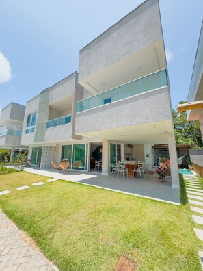 A modern multi-story building with a flat roof, large glass windows, and a well-maintained lawn. - House with Private Pool in Maragogi – Praia de Antunes (Maragogi)