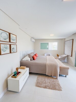 A modern bedroom with a bed, bedside table, and a chair. There are framed pictures on the wall and a window with blinds. - House with Private Pool in Maragogi – Praia de Antunes (Maragogi)