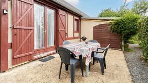 A patio with a table and chairs, a red barn-like structure, and a gravel path.