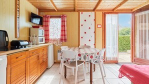 A cozy kitchen with wooden cabinets, a dining table with chairs, a TV, and a microwave.