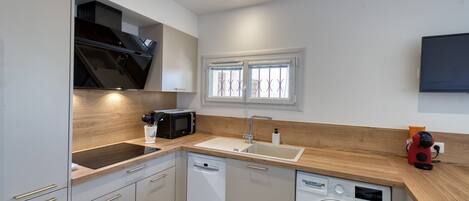 A modern kitchen with a dishwasher, microwave, sink, and a washing machine.