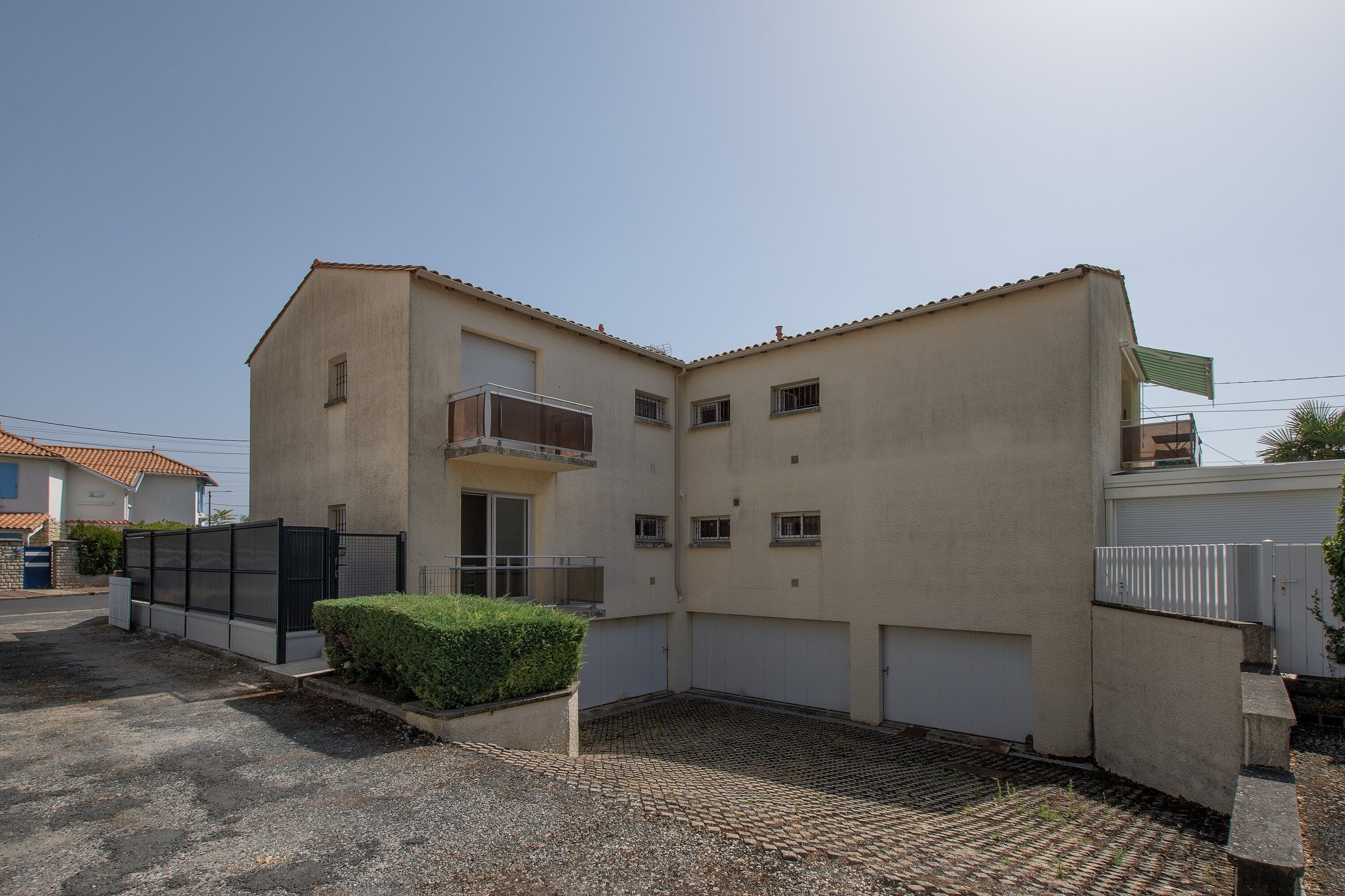 Un bâtiment à deux étages, doté d’un toit plat, d’un balcon au deuxième étage et d’une entrée fermée par un portail.