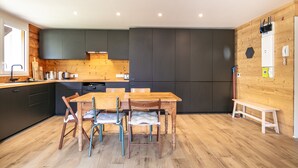 A modern kitchen with dark cabinets, a wooden dining table, and chairs.