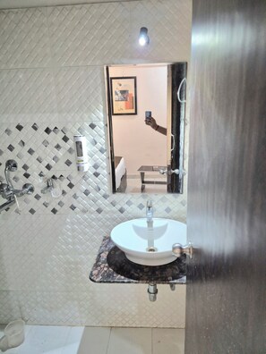 A bathroom with a white sink, a mirror, and a shower.