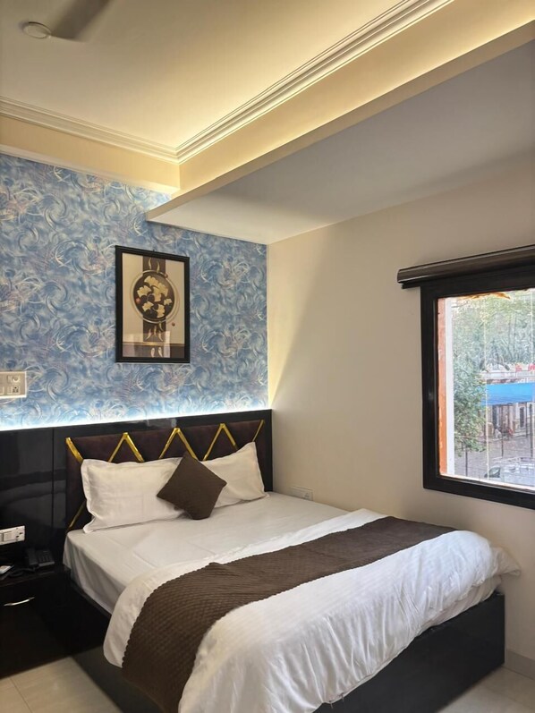 Un dormitorio con cama, mesita de noche, una obra de arte en la pared y ventana con vistas.