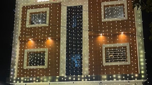 A hotel with a sign reading "HOTEL D.C. GRAND" at night, featuring a modern facade with string lights and a central entrance with steps. - HOTEL D C GRAND (Varanasi)