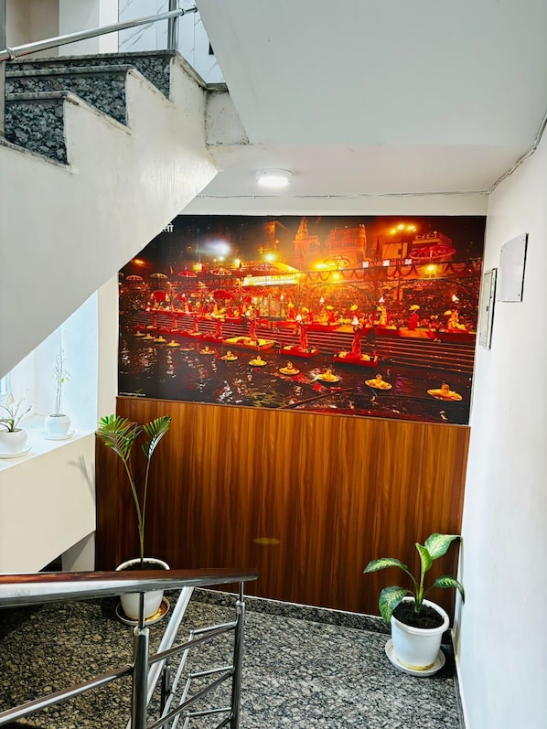 A modern hotel interior with a staircase, a wooden panel wall, and potted plants.