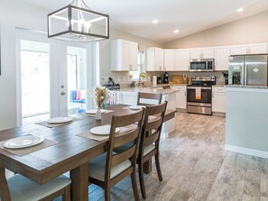 Una cocina moderna con armarios blancos, una mesa de comedor de madera y un horno empotrado.