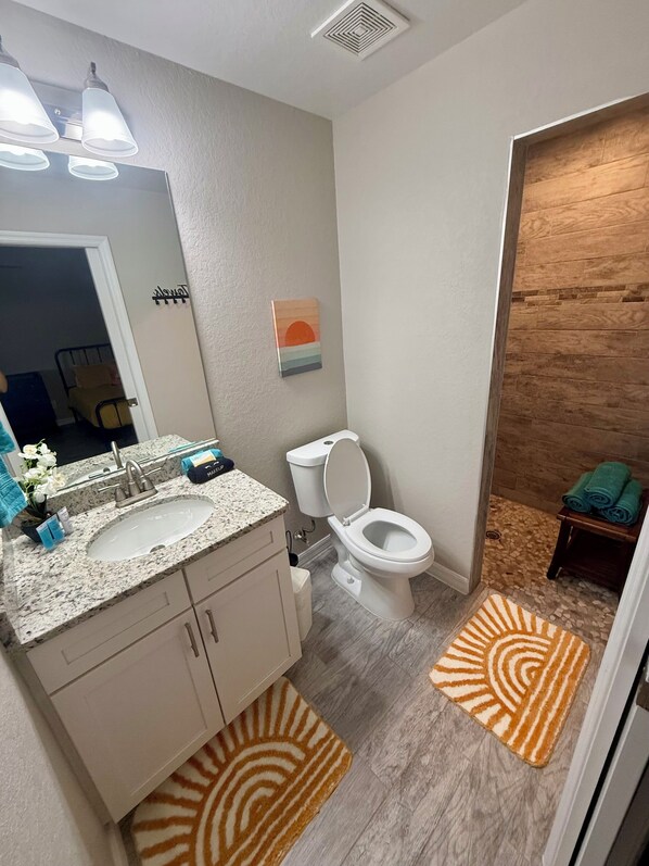 Un baño con lavamanos, inodoro y zona de ducha.
