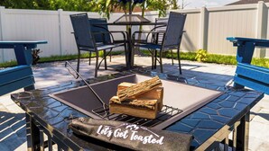 An outdoor patio with a fire pit, chairs, and a table. - Family Beach Retreat w/ Private Fenced Backyard, Fire Pit, Games (Englewood)