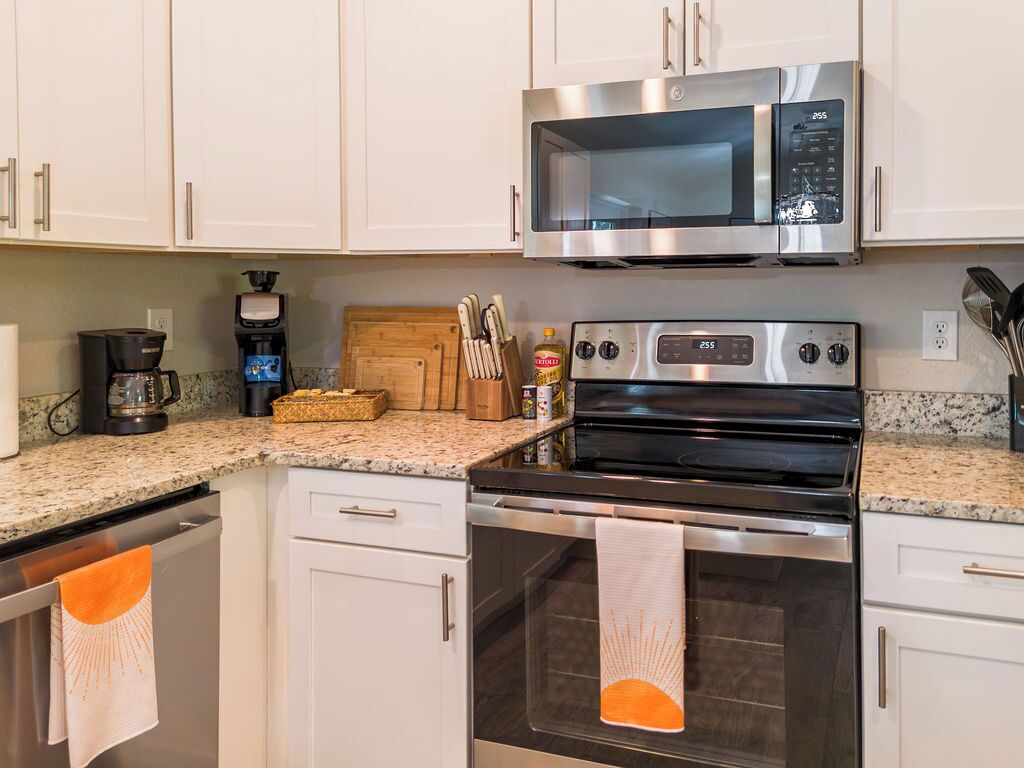 A modern kitchen with stainless steel appliances, including a microwave and oven, and a granite countertop.