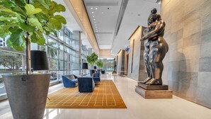 A modern lobby with a large planter, seating area, and a statue.