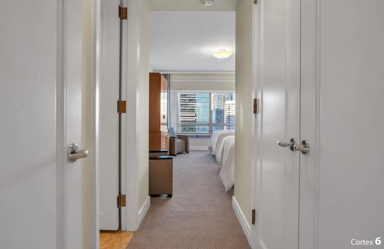 Un couloir d’hôtel avec un lit, un bureau et une fenêtre donnant sur la ville.