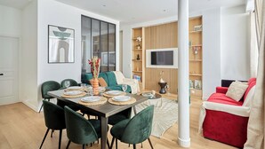 Una sala de estar moderna con comedor, un sofá rojo y un televisor montado en la pared.