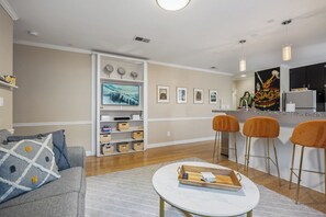 Un salon moderne avec un canapé, une table basse et un coin cuisine équipé de tabourets de bar.