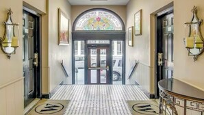 Eine Hotelhalle mit Fliesenboden, einem Kronleuchter und einem Buntglasfenster über dem Eingang.