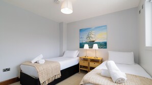 Habitación de hotel con dos camas, un cuadro de un barco en la pared y una ventana con cortinas.