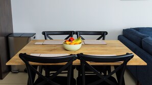 Una mesa de comedor con un frutero, sillas negras y un sofá azul al fondo.