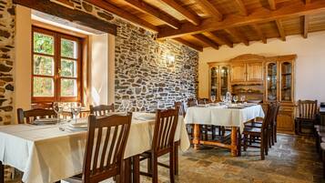 A dining area with stone walls, wooden beams, and tables set for dining.