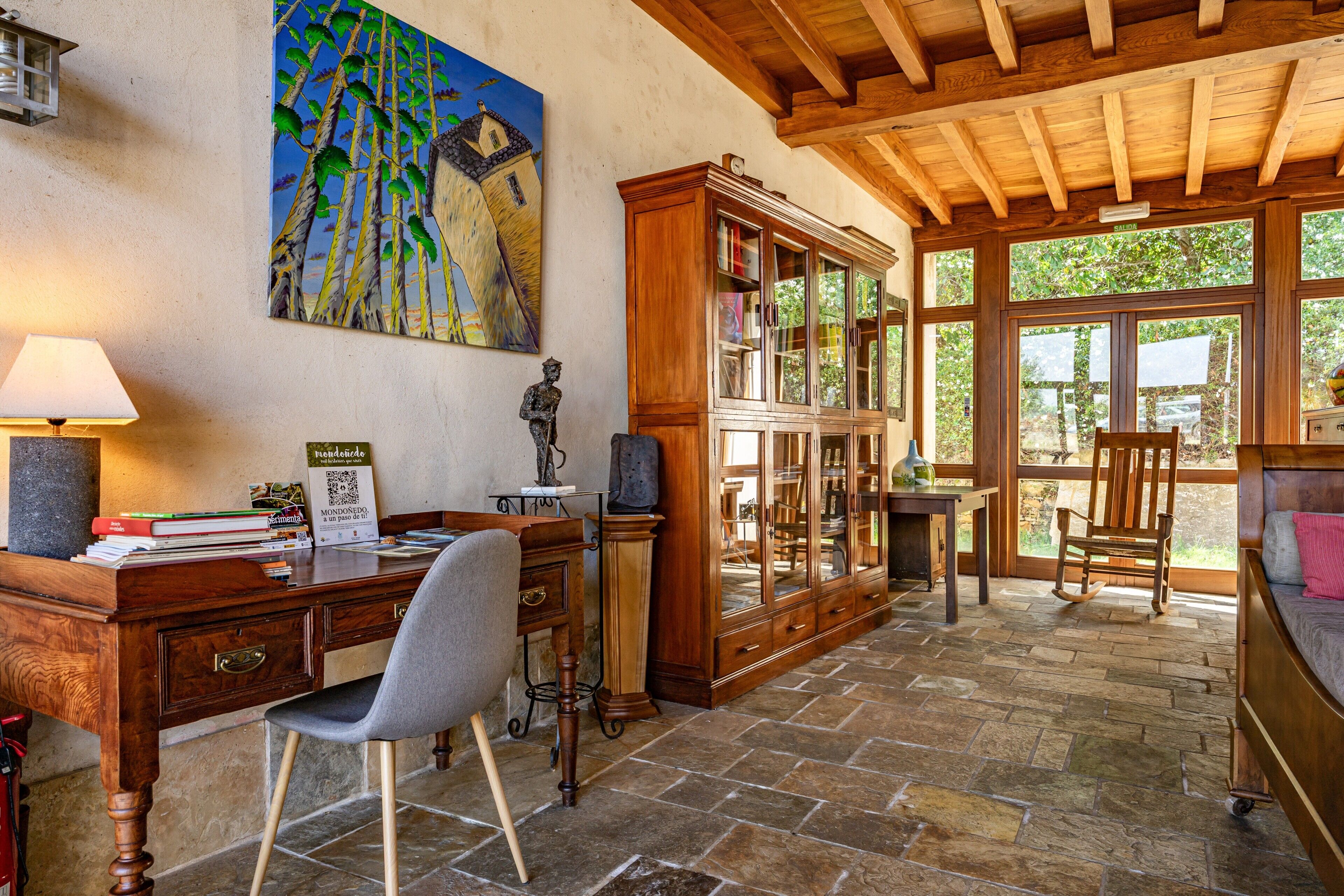 Una habitación con escritorio de madera, una silla, un armario y una cama.