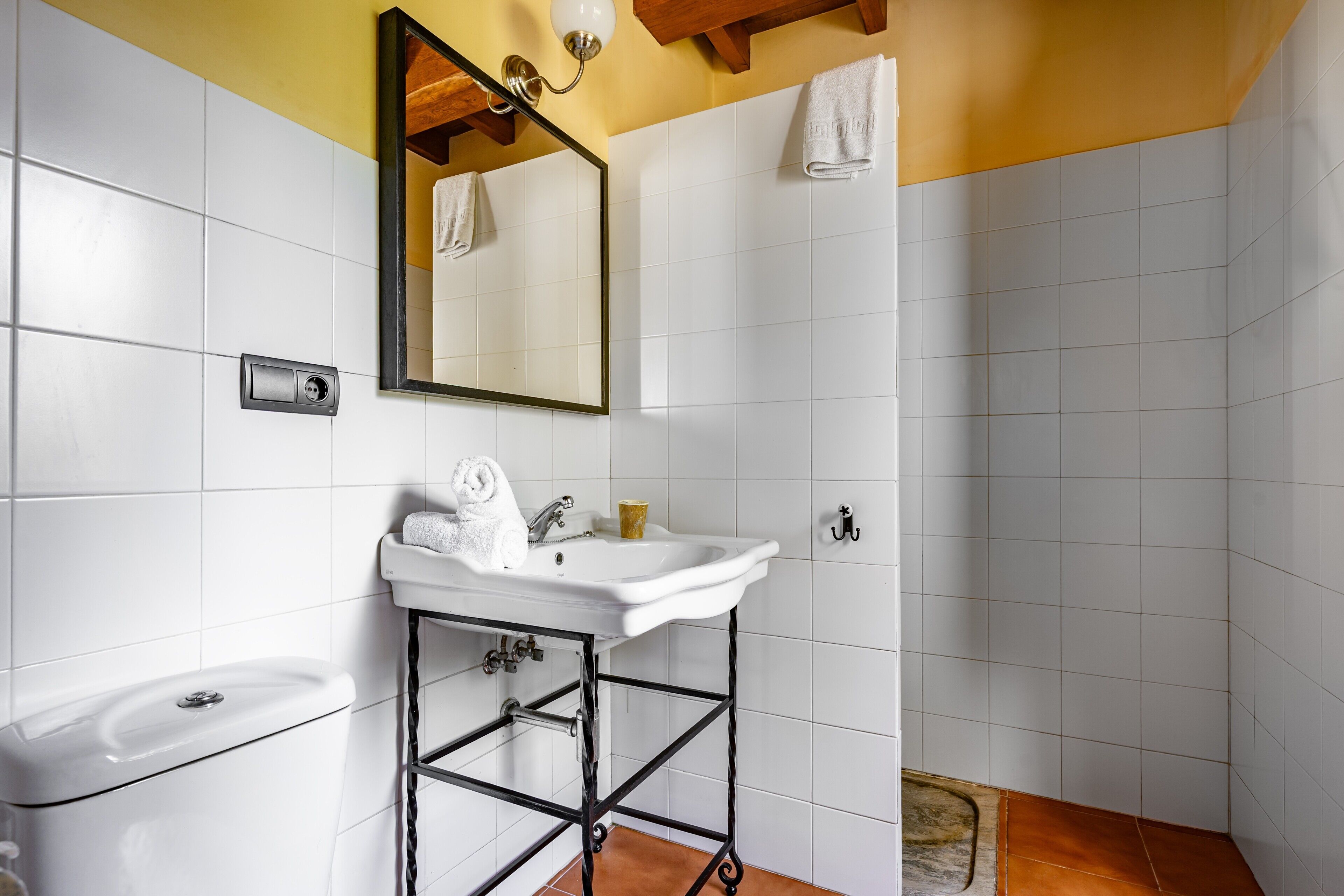 A bathroom with a white sink, mirror, and toilet, a towel rack, and a shower area.