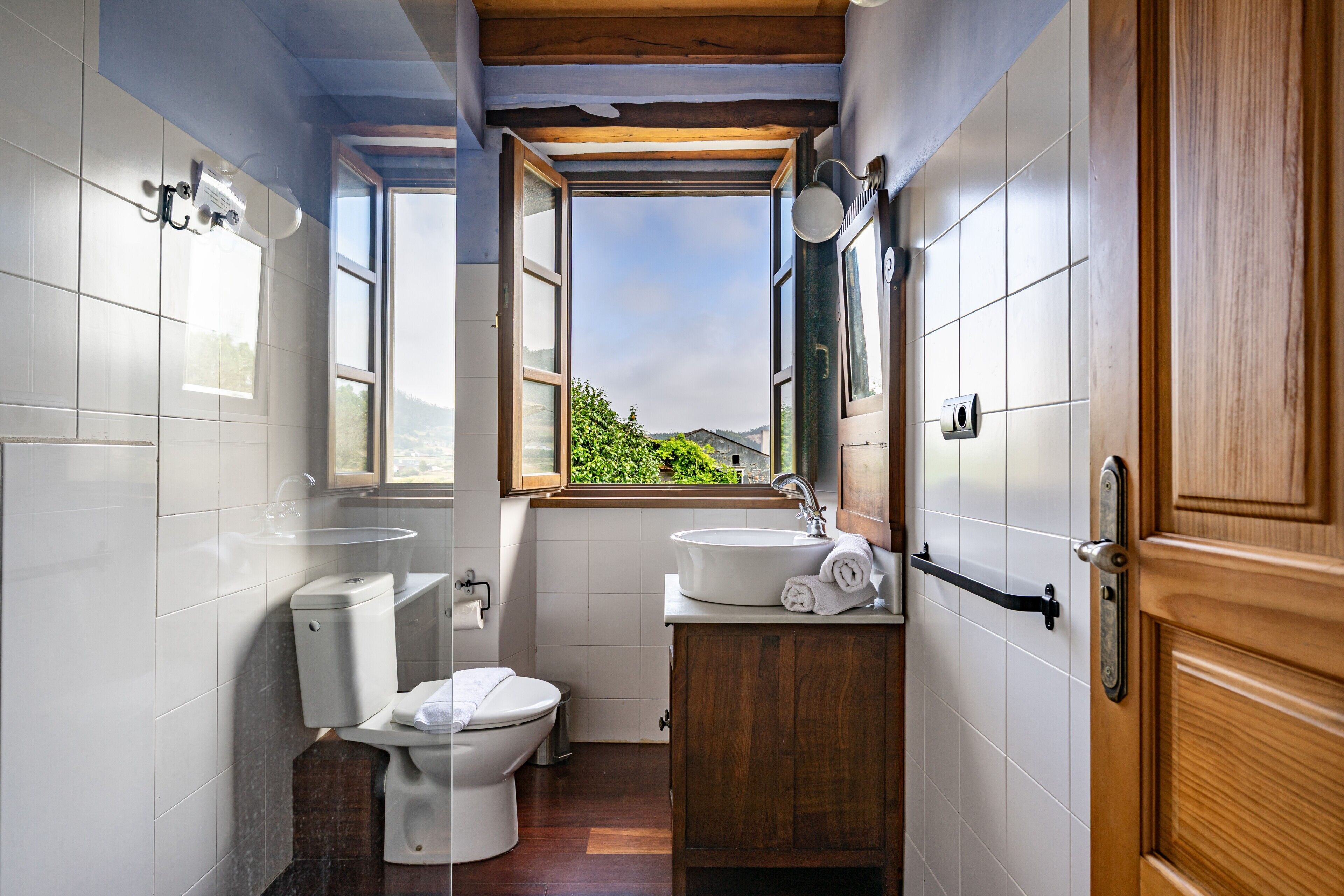 A bathroom with a toilet, sink, and window.