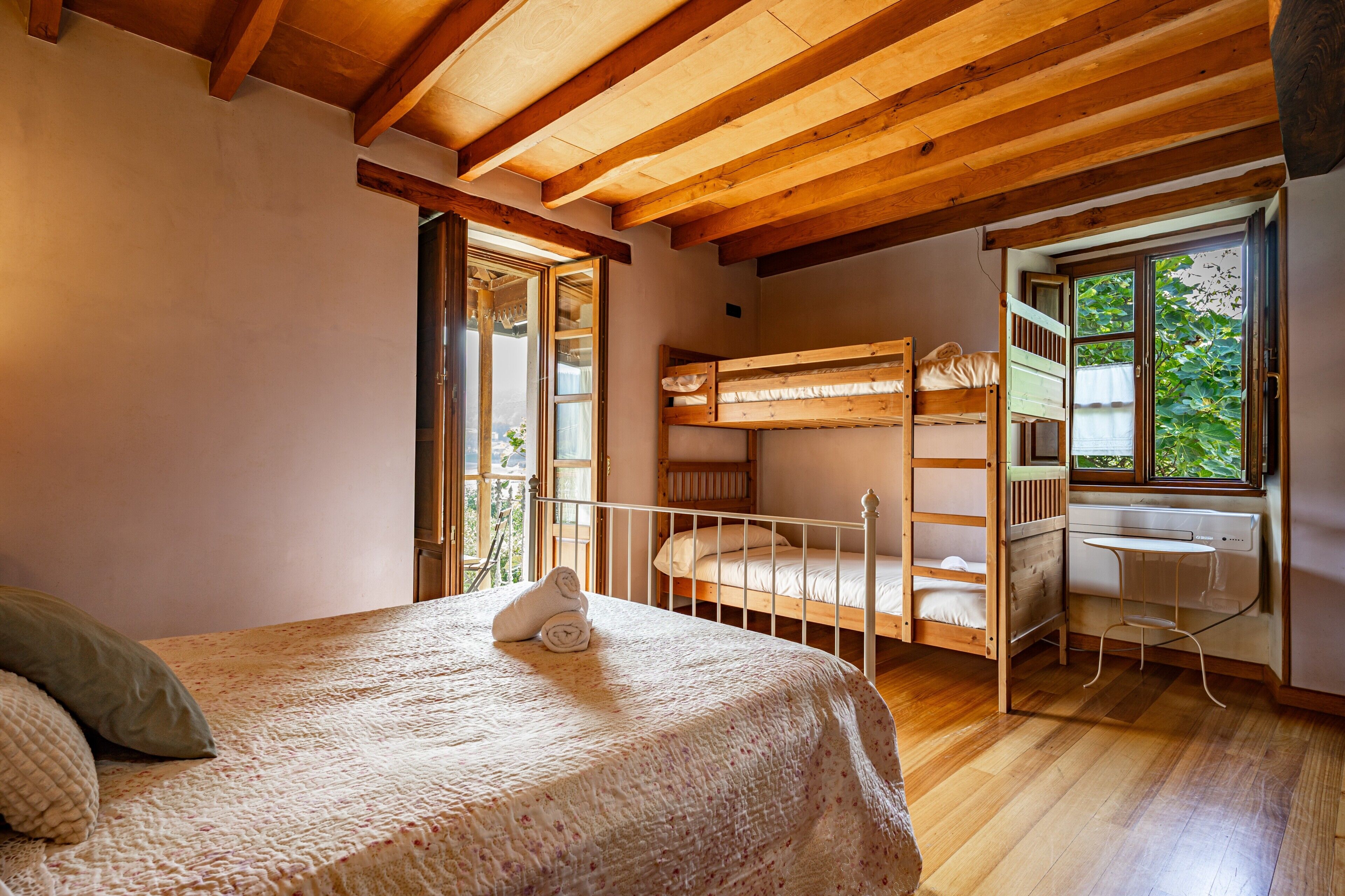Une chambre avec un lit superposé, un bureau et une fenêtre donnant sur un paysage verdoyant.