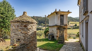 A stone building with a small tower, a paved pathway, and a grassy area with trees.