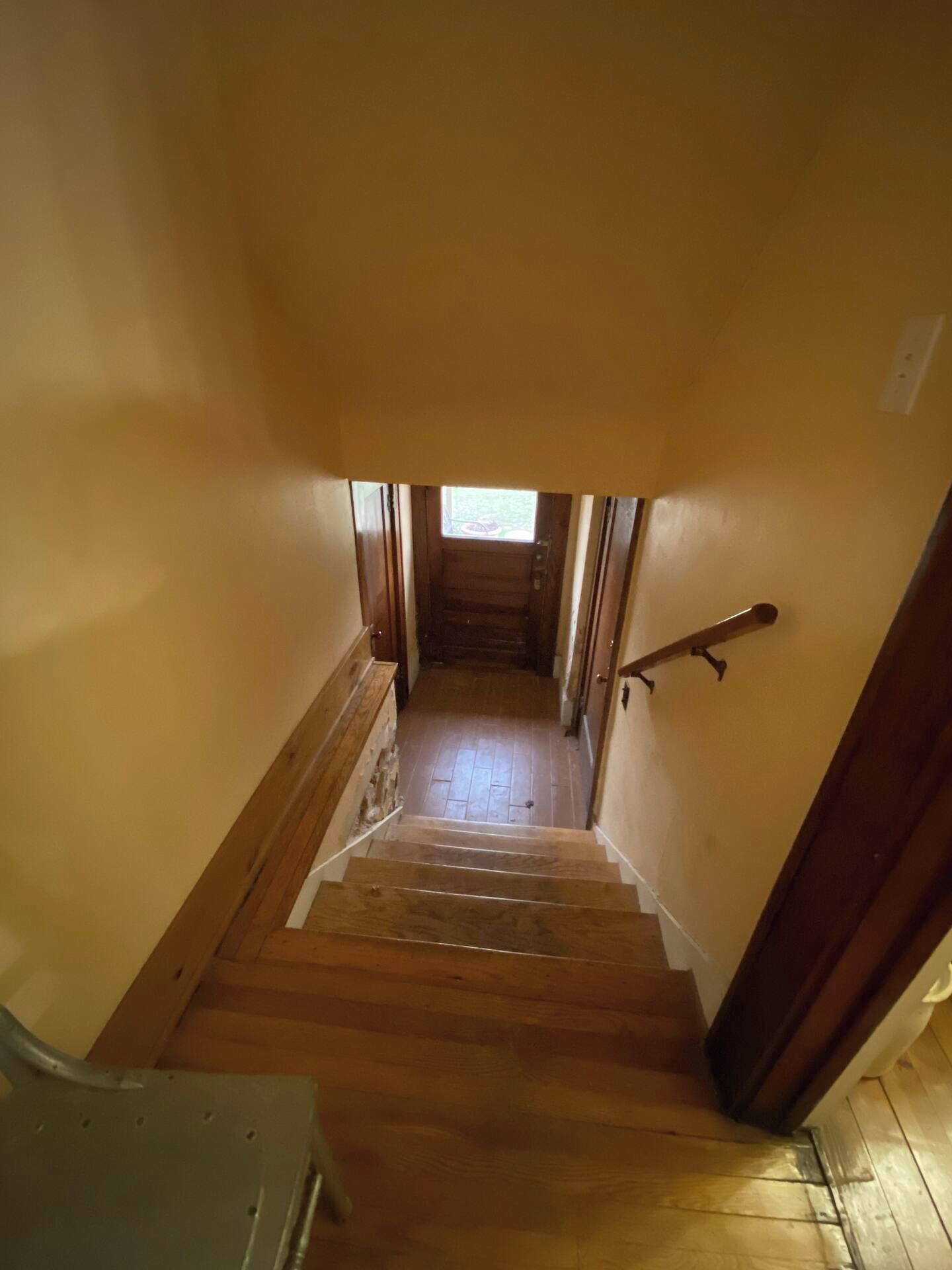 A wooden staircase leading to a second floor with a small window at the top.